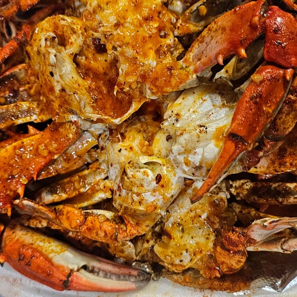 Close-up of seasoned crab legs and claws, showcasing the vibrant orange and white shells.
